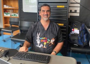 Dr Juergen sitting at desk and smiling, at a medical clinic for people experiencing homelessness or vulnerability